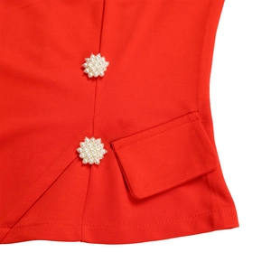 Close-up of red top fabric featuring decorative white pearl buttons and pocket flap detail