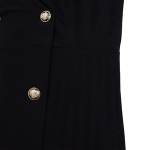 Detailed close-up of golden lion crest buttons on black pleated blazer dress fabric