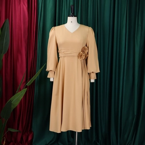 Detail of the elegant khaki dress showing V-neck, floral waist decor, and side pleats