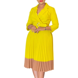 Détail d'une robe plissée jaune avec un ourlet contrasté kaki et une ceinture élégante