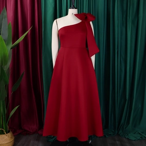 Detail of elegant burgundy one-shoulder gown featuring a large bow and floor-length skirt