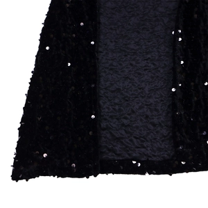 Macro detail of black velvet fabric with shimmering silver sequins and pleated texture