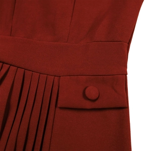 Detailed view of high-waist pleated red dress with decorative pocket and fabric button