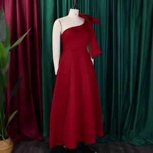 Detail of red one-shoulder gown featuring a large structural bow and sleek A-line skirt