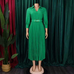 Detail of green long-sleeve pleated dress featuring a V-neck and belt with metal buckle