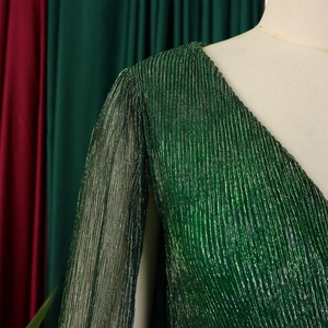 Detail of elegant V-neck dress featuring sparkling green pleated fabric and sheer sleeves