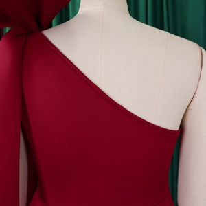 Detail shot of the burgundy one-shoulder dress featuring a large bow and premium fabric