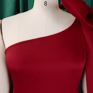 Detailed close-up of a red one-shoulder dress showing the large bow and elegant neckline