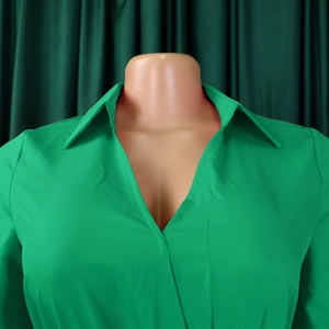 Close-up of the elegant V-neck notched collar on a pleated emerald green dress