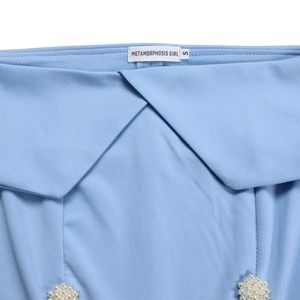 Detail of elegant light blue off-shoulder dress featuring pearl floral buttons and texture
