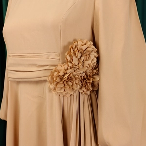 Detail view of handmade fabric flowers and pleated waist on an elegant apricot dress