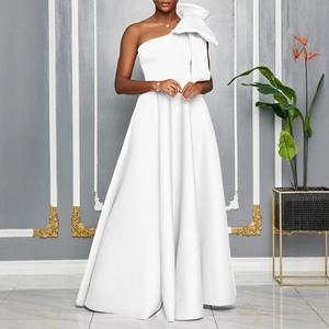 Detail of elegant one-shoulder white gown featuring a large decorative bow and floor-length hem