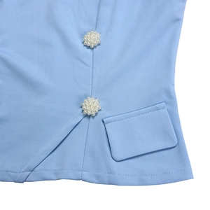 Macro shot of sky blue garment showing luxury pearl floral buttons and pocket detail