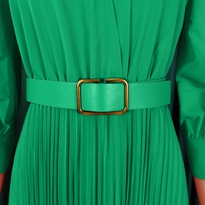 Detail of green pleated dress featuring a matching waist belt and gold metal buckle