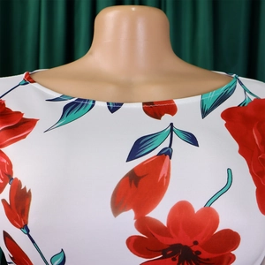 Vue détaillée du col rond et de l'imprimé floral rouge vif sur le tissu blanc chic