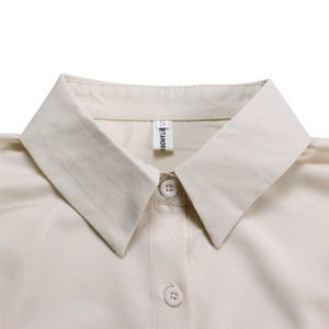 Close-up of lapel collar and buttons on a beige loose-fit long sleeve shirt dress