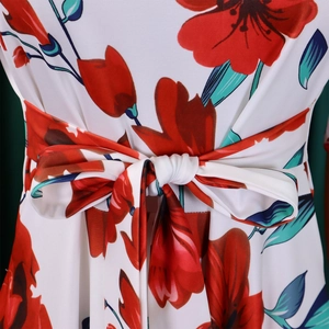Gros plan du nœud à la taille sur robe blanche aux motifs de fleurs rouges vives