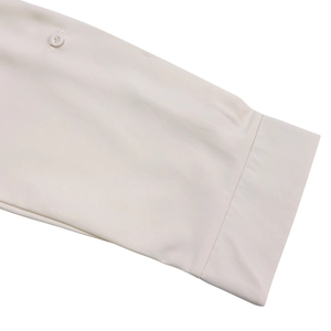 Detail of the beige shirt sleeve cuff showing the smooth woven fabric and button closure