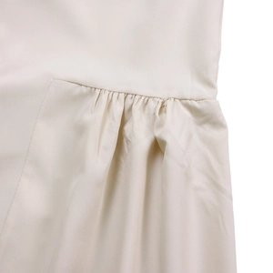 Detailed close-up of pleated beige cotton-linen fabric with professional stitching seams