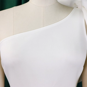Close-up of white one-shoulder evening dress featuring a large bow detail on the neckline