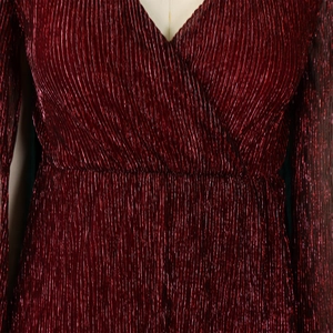 Detail of burgundy pleated dress with metallic sheen and elegant V-neck design