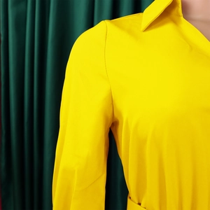 Detailed view of bright yellow V-neck dress collar and long sleeve shoulder seams