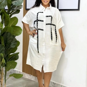 Close-up of white shirt dress featuring black straps with silver metal rivet details