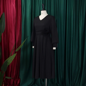 Detail of a black V-neck pleated dress featuring a 3D floral accent on the waistline