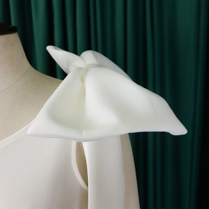 Detail of elegant one-shoulder white dress with a large decorative bow on a mannequin