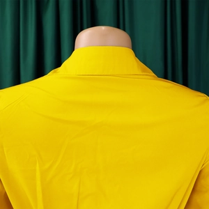 Detail view of bright yellow V-neck dress collar and pleated back craftsmanship