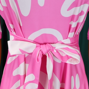 Close-up of pink African print dress featuring a tied bow belt and elastic fabric texture
