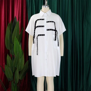 Detail of white shirt dress featuring black decorative ribbons and silver metal studs