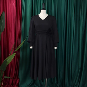 Close-up of elegant V-neck dress with pleated skirt detail and 3D floral waist belt