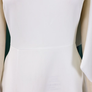 Detail of waist tailoring and stitching on white one-shoulder maxi dress fabric
