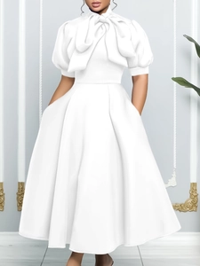 Elegant white summer dress with puff sleeves, high neck bow, and full flared skirt