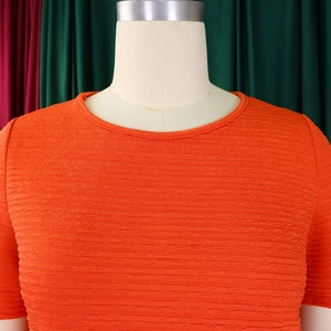 Détail du haut orange vif à col rond montrant la texture gaufrée horizontale sur un mannequin