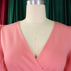 Detail of pink V-neck dress featuring wrap design and textured fabric on mannequin