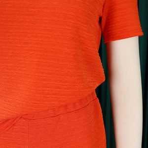 Détail de la texture du tissu crêpe orange vif sur un ensemble d'été moderne à manches courtes