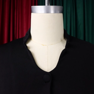 Detail of black stand-up collar top showing ribbed texture and fabric button on mannequin