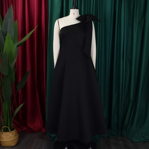 Detail of elegant black one-shoulder evening gown with large bow accent on mannequin