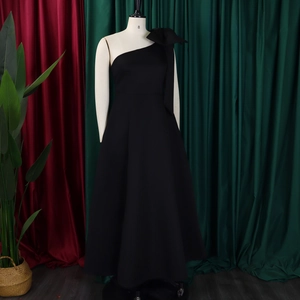 Detail of elegant black one-shoulder evening gown with oversized shoulder bow decoration
