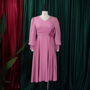 Detailed view of dark pink V-neck dress with long sleeves and pleated side flower detail