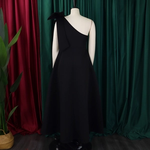 Detail of the back and side view of a black one-shoulder evening gown with big bow decoration