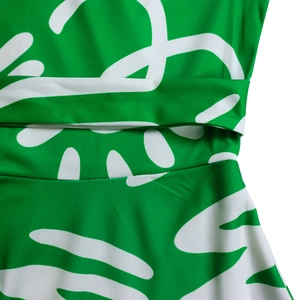 Detailed view of green African print dress waistline with belt and abstract patterns