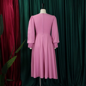 Back view of elegant pale pink A-line dress with long sleeves and flared skirt detail