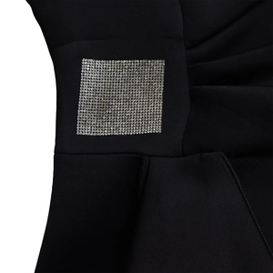 Close-up of elegant rhinestone buckle and ruffled fabric detail on black dress