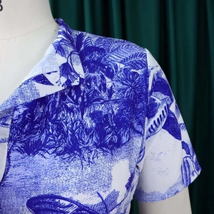 Détail de l'imprimé tropical bleu sur robe blanche à manches courtes et col à revers