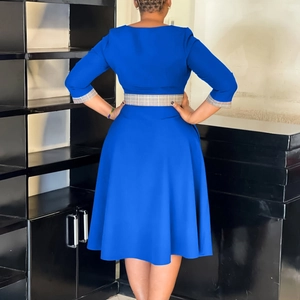 Rear view of royal blue A-line dress with plaid trim on waist and cuffs, midi length