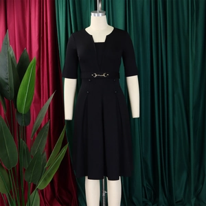 Détail d'une robe trapèze noire avec col en V et ceinture décorative à boucle dorée