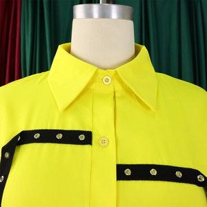 Detail of yellow loose shirt showing lapel collar, buttons and eyelet ribbon decoration